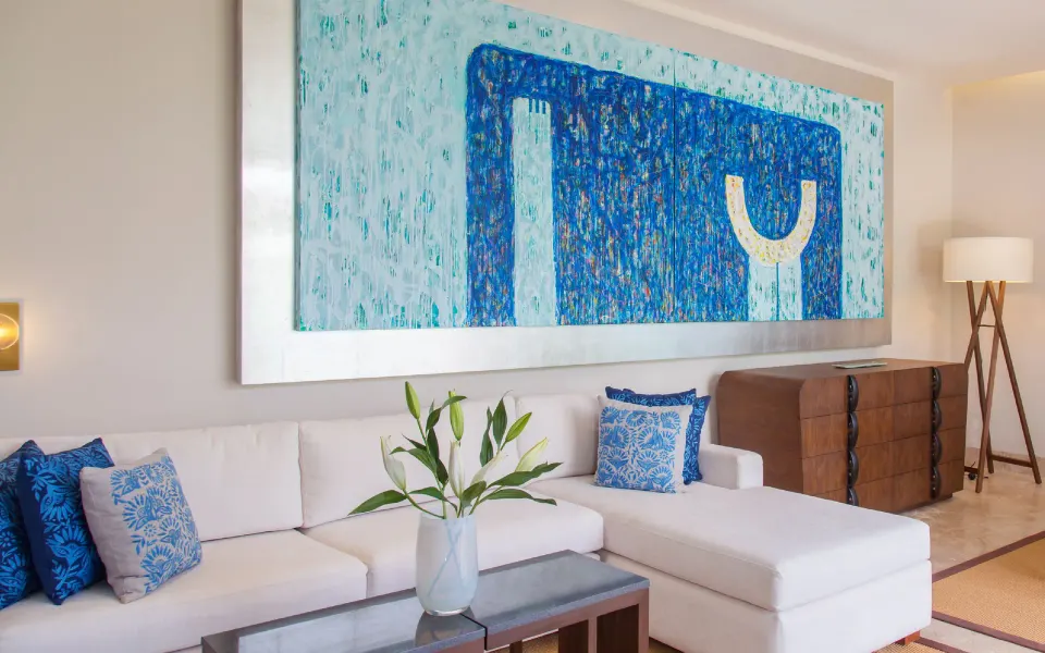 White sectional sofa with blue pillows and abstract blue painting at Chablé Yucatán