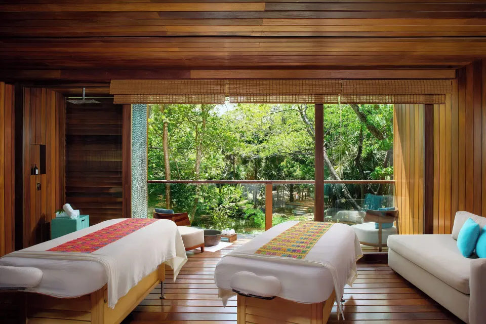 Two massage tables in a wooden spa room at Chablé Yucatán with forest view.