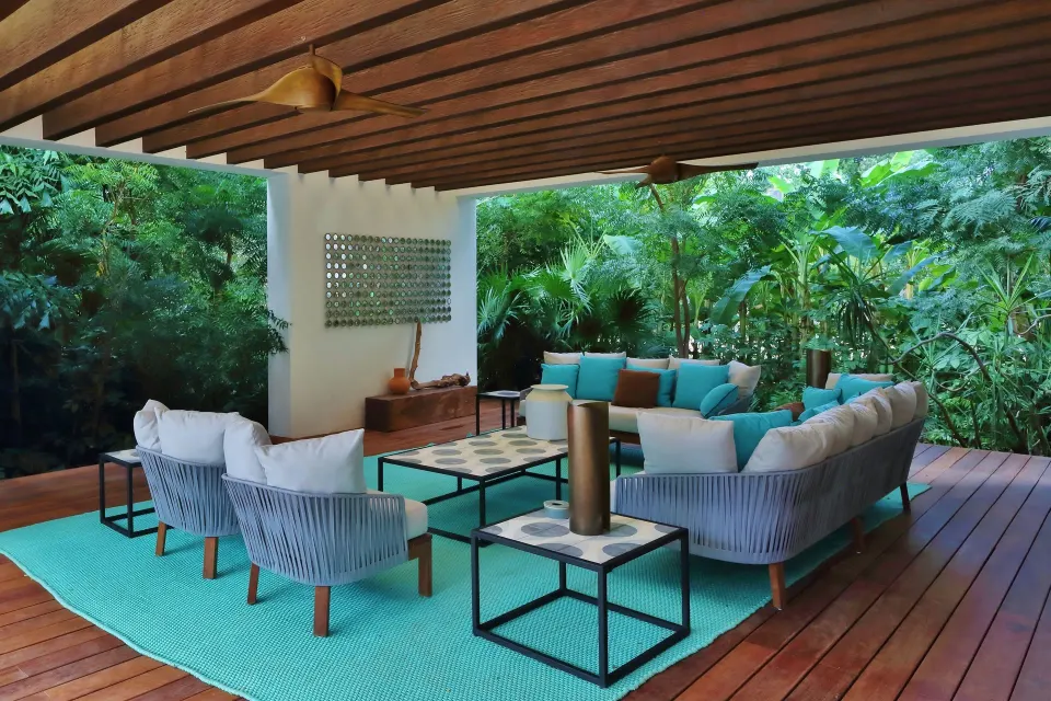 Shaded outdoor lounge with turquoise cushions and wooden deck at Chablé Yucatán