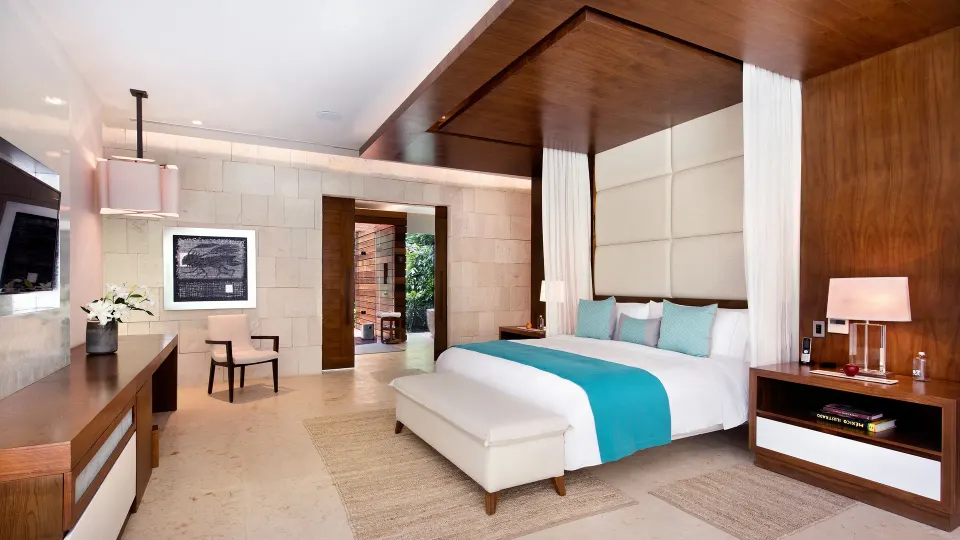 King bed with turquoise accent runner and desk in a guest room at Chablé Yucatán