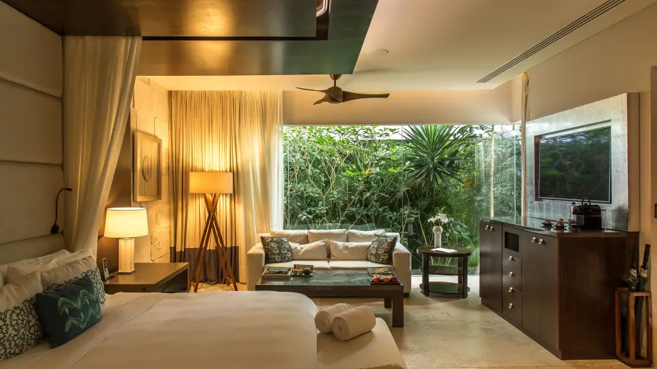 Bed, sofa and garden-view window in a guest room at Chablé Yucatán