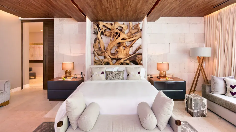 Guest room with king bed, sculptural headboard and seating area at Chablé Yucatán