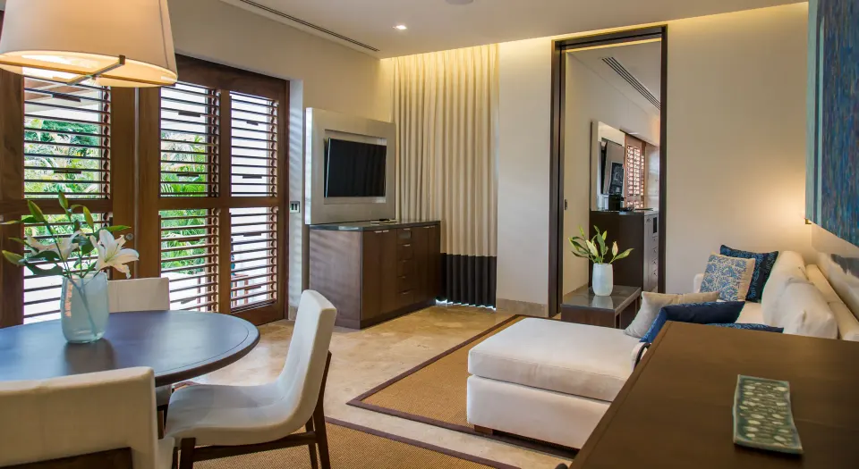 Suite interior with dining table, shuttered windows and lounge area at Chablé Yucatán