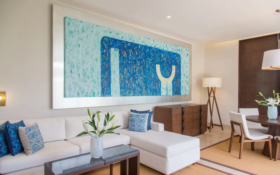 Bright living area with white sectional sofa and blue artwork at Chablé Yucatán