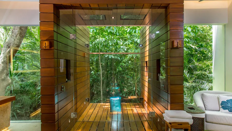 Wood-lined open shower and seating area framed by jungle at Chablé Yucatán