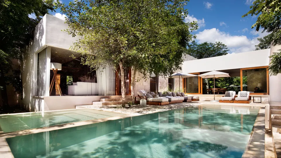 Long rectangular pool with loungers and shaded patio at Chablé Yucatán