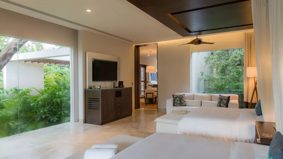 Spacious guest room with two beds and large glass openings at Chablé Yucatán