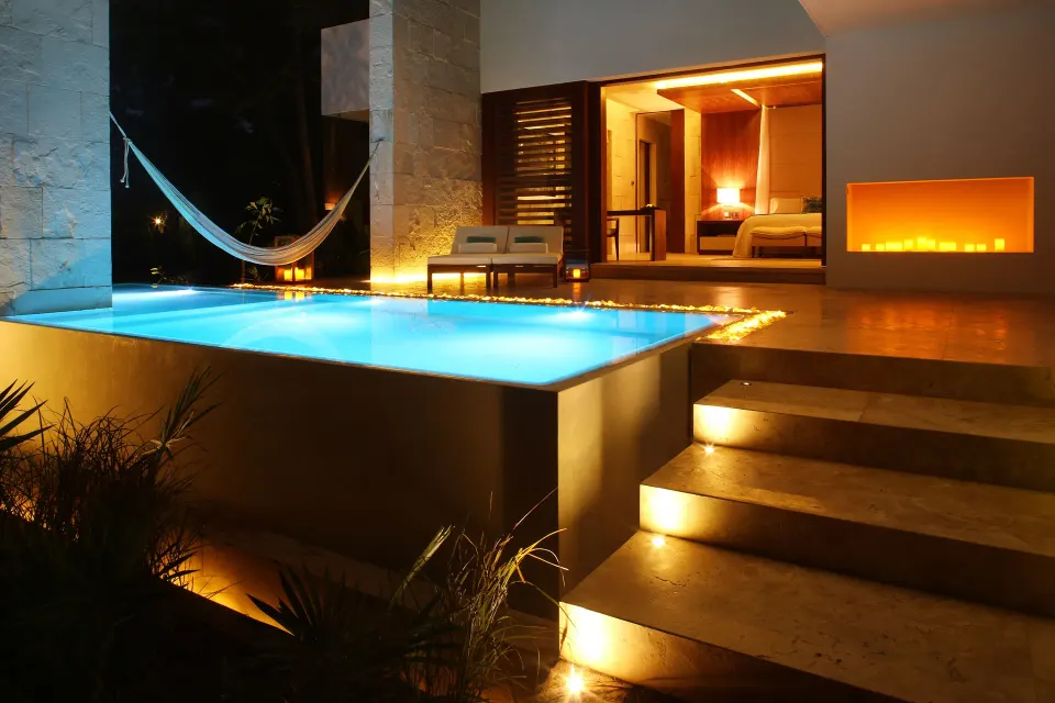 Villa pool at night with hammock and king bed visible inside at Chablé Yucatán