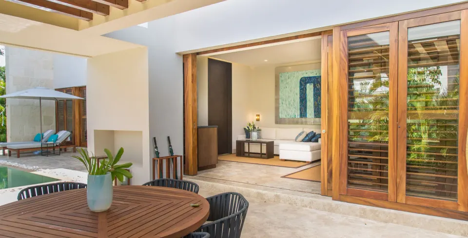 Terrace dining table and poolside lounge seen through sliding wood doors at Chablé Yucatán