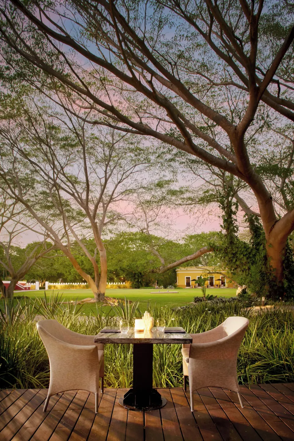 Two dining chairs and table overlooking lawns and trees at Chablé Yucatán