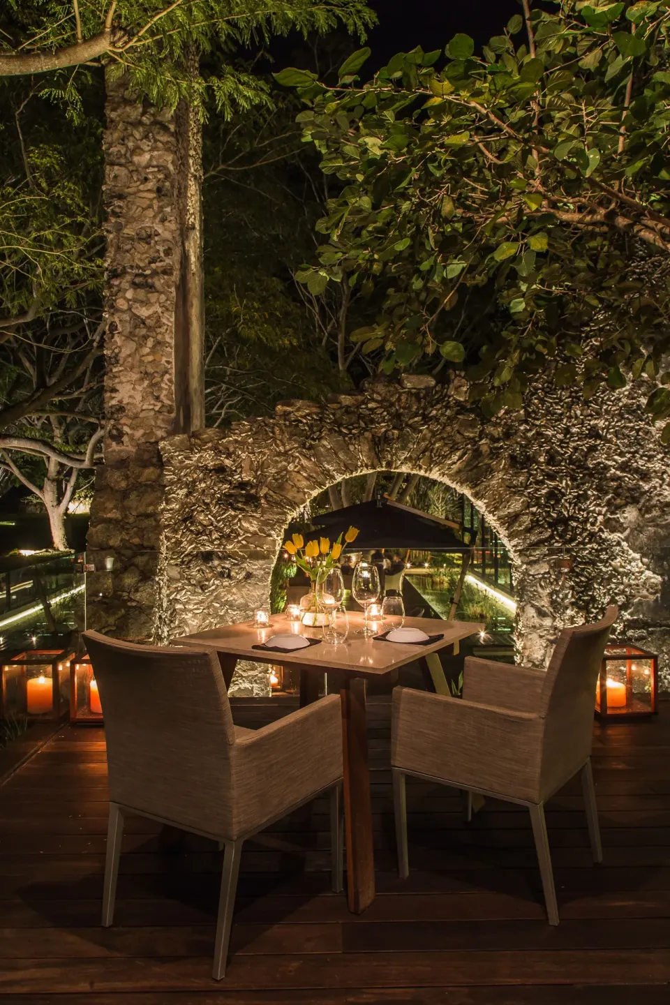 Romantic candlelit outdoor dining table by stoned wall at Chablé Yucatán