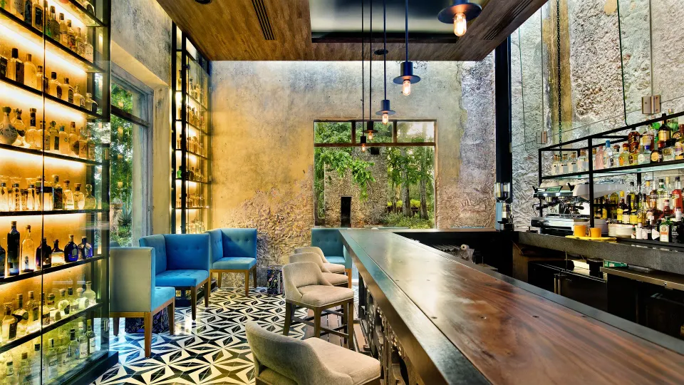 Intimate bar interior with wood counter and backlit shelving at Chablé Yucatán