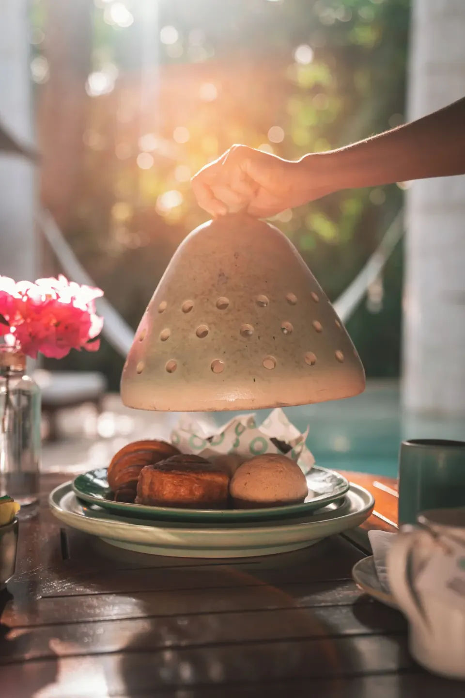 Hand lifting cloche from plate of pastries by pool at Chablé Yucatán