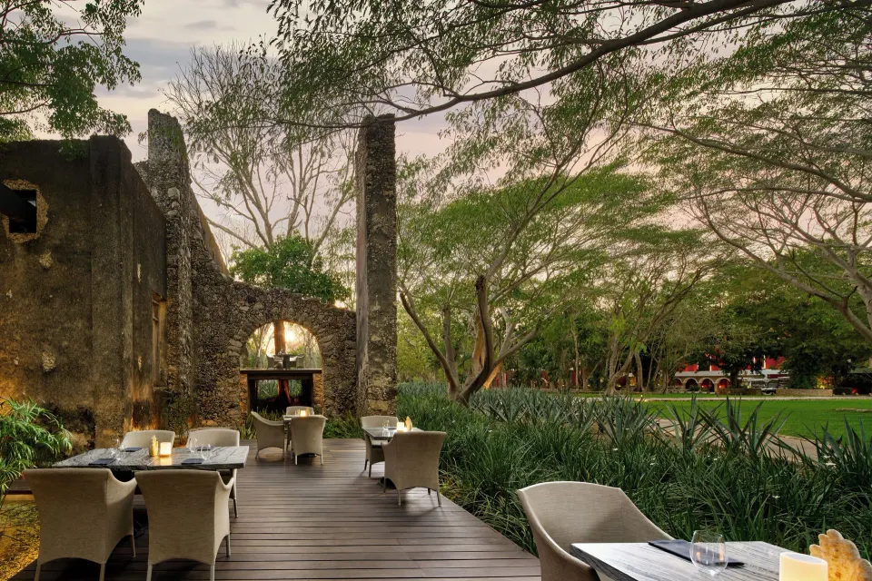 Deck dining beside restored stone ruins and lawn at Chablé Yucatán