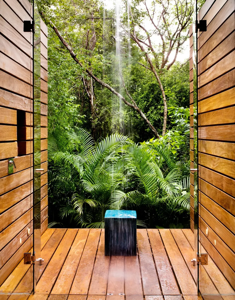 Outdoor rainforest shower framed by wooden doors in a Casita at Chablé Yucatán.