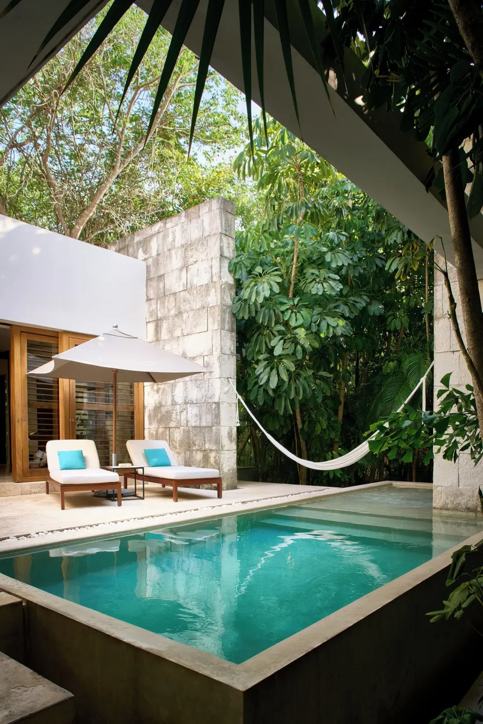 Private pool terrace with loungers, umbrella and hammock framed by tropical foliage at Chablé Yucatán