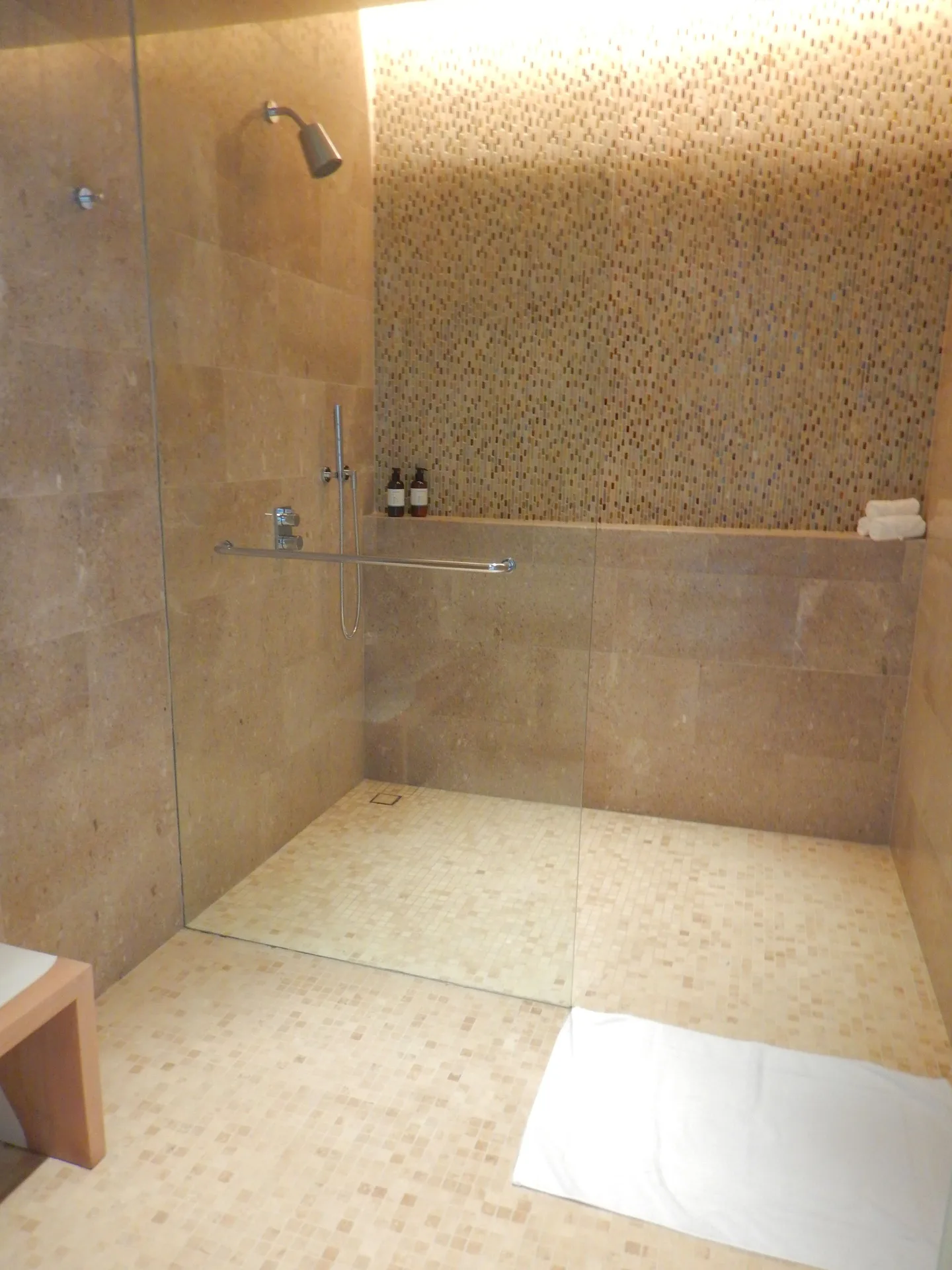 Glass-enclosed shower with mosaic tile inside a bathroom at Chileno Bay Resort & Residences.