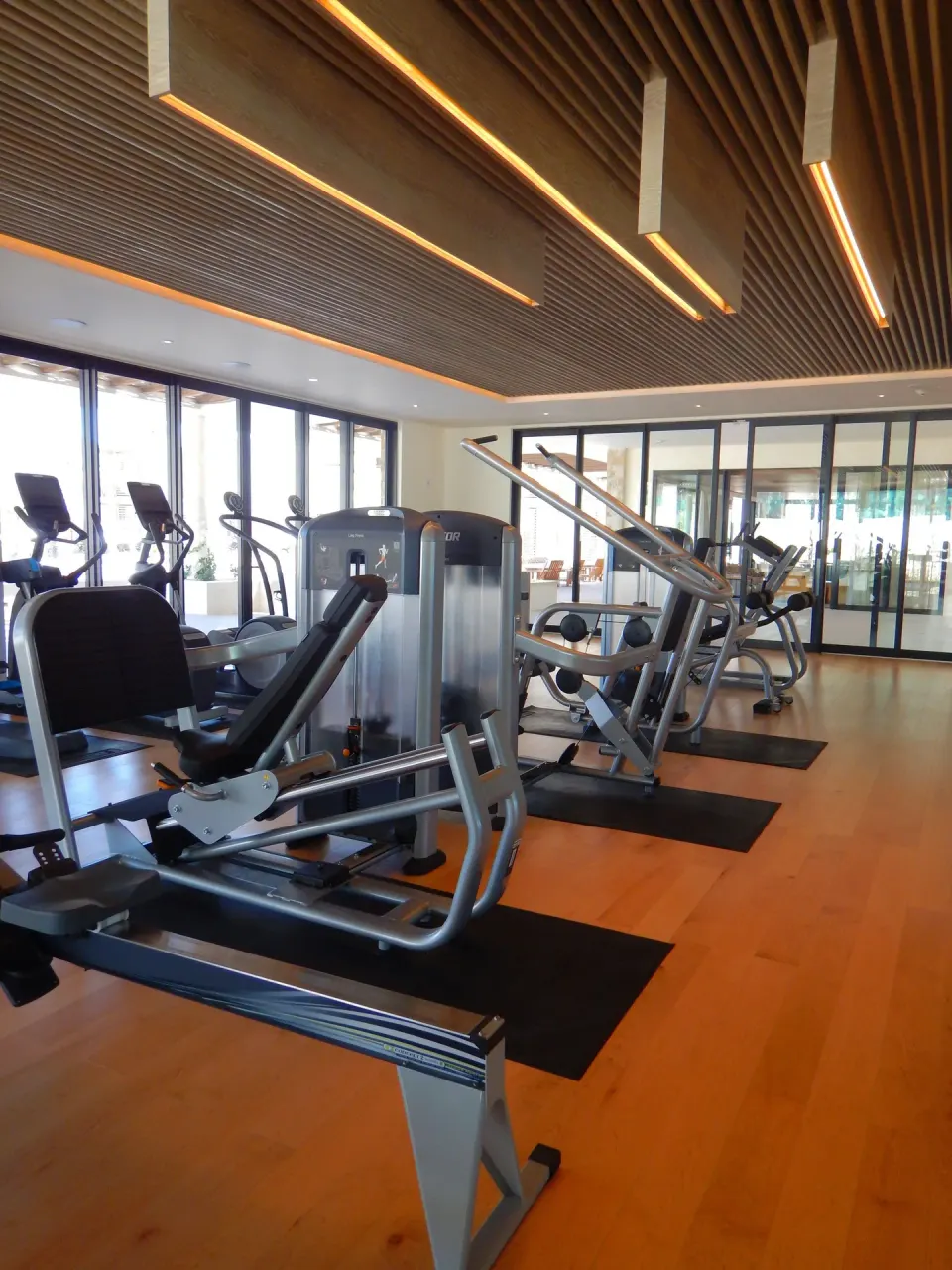 Cardio and strength machines beneath a wood-slat ceiling at Chileno Bay Resort & Residences.