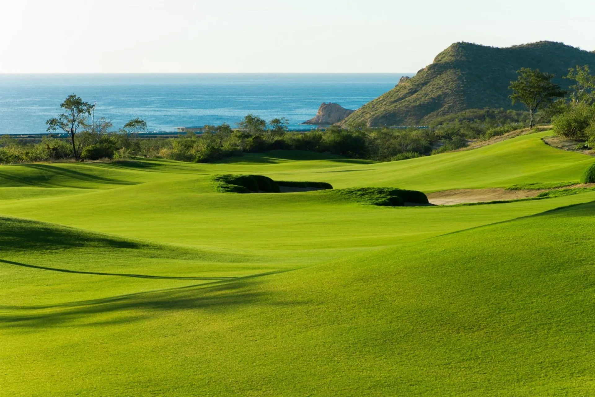 A green golf course overlooks the ocean near Chileno Bay Resort & Residences.