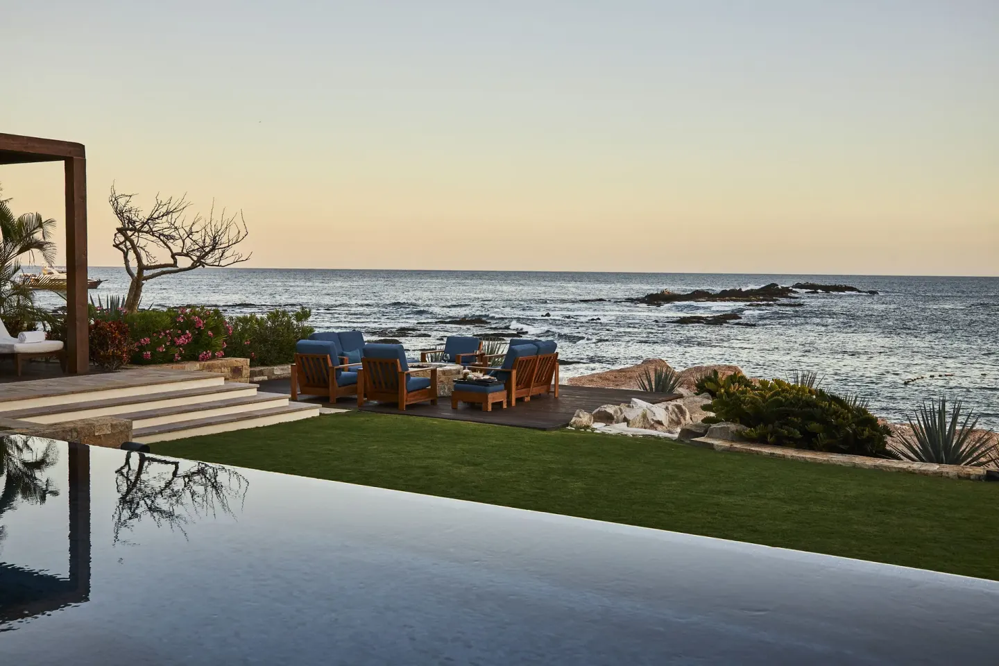 Oceanfront lawn seating and infinity pool at Chileno Bay Resort & Residences.