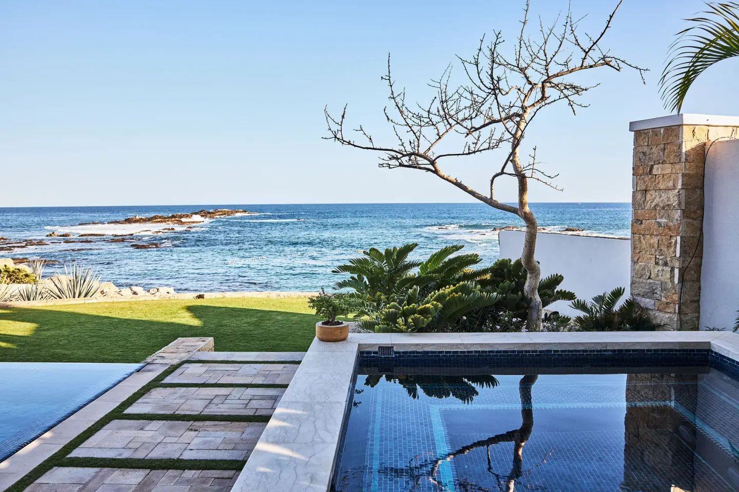 Oceanfront pool terrace with rocky shoreline at Chileno Bay Resort & Residences.