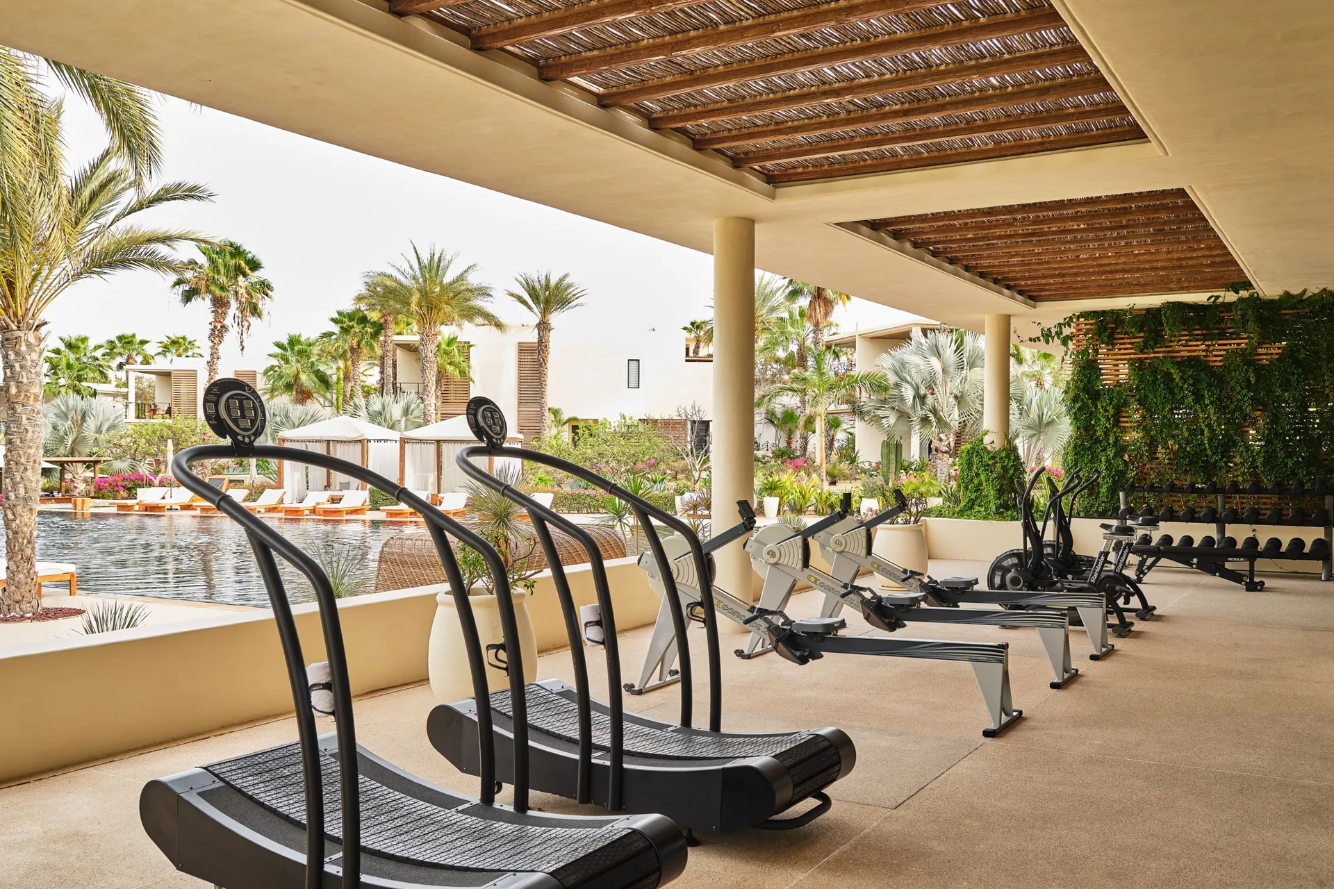 Open-air gym cardio equipment overlooking the pool at Chileno Bay Resort & Residences.
