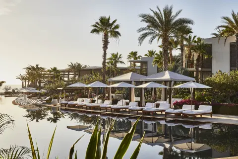 Pool loungers, umbrellas, palms, and resort buildings at Chileno Bay Resort & Residences.