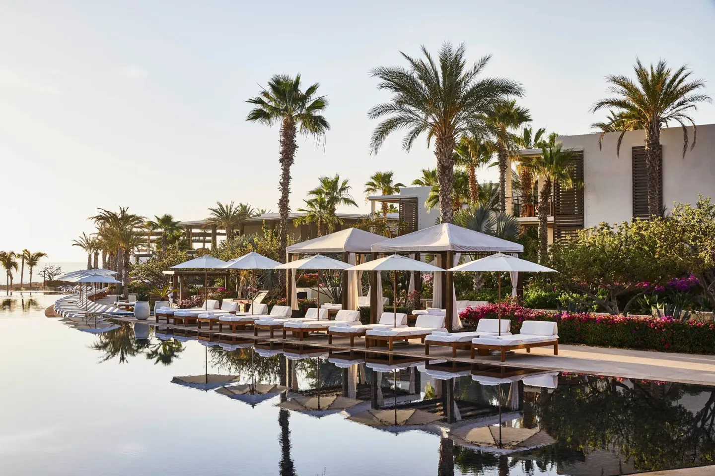 Poolside loungers and cabanas beside palms at Chileno Bay Resort & Residences.