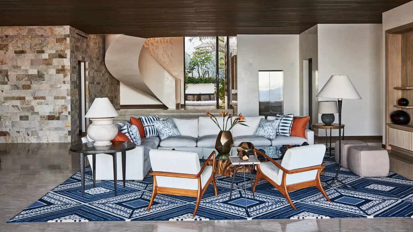 Living room with patterned rug and spiral stair at Chileno Bay Resort & Residences.