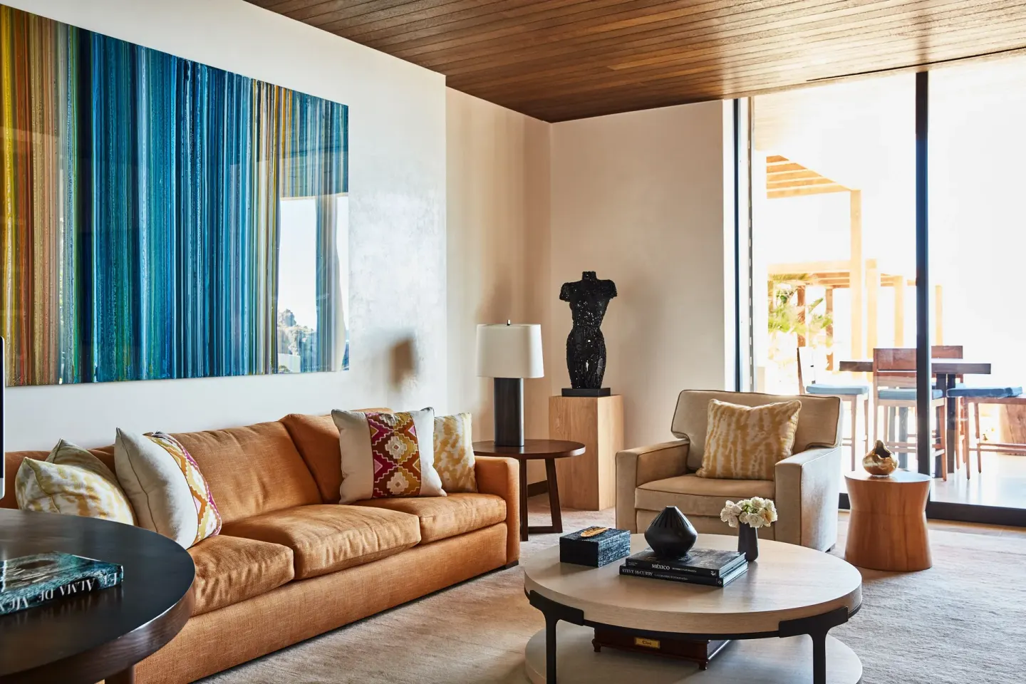 Sitting area with tan sofa and colorful wall art at Chileno Bay Resort & Residences.