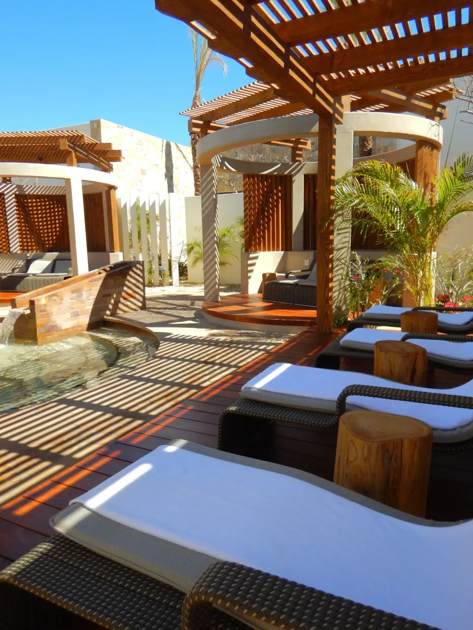 Spa courtyard lounge chairs and pergolas by a water feature at Chileno Bay Resort & Residences.
