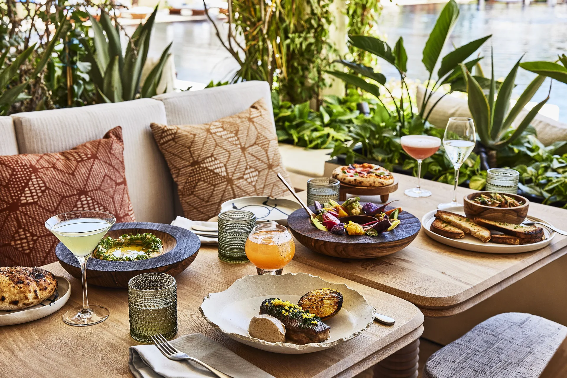 Table of plated dishes and cocktails at Chileno Bay Resort & Residences.