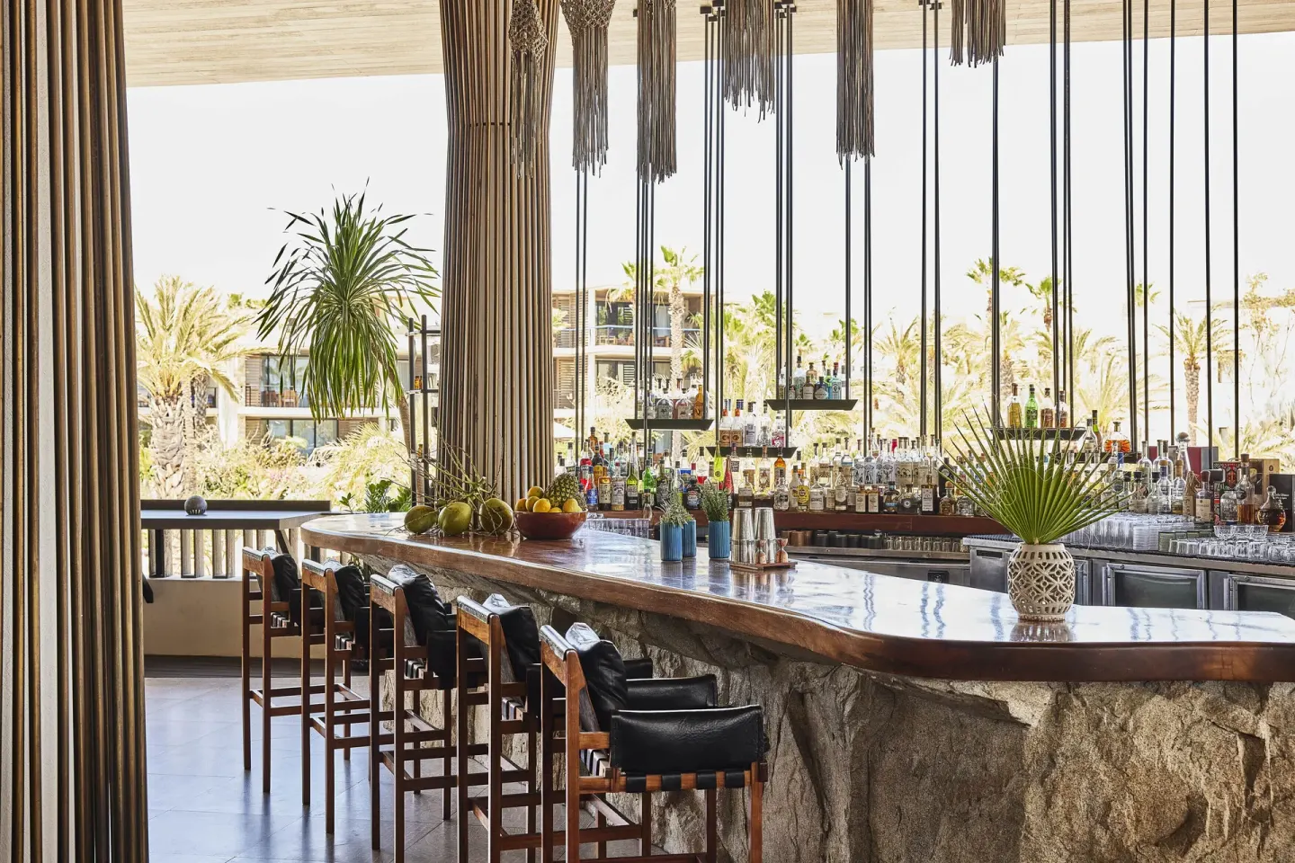 Stone bar with high stools and hanging decor at Chileno Bay Resort & Residences.