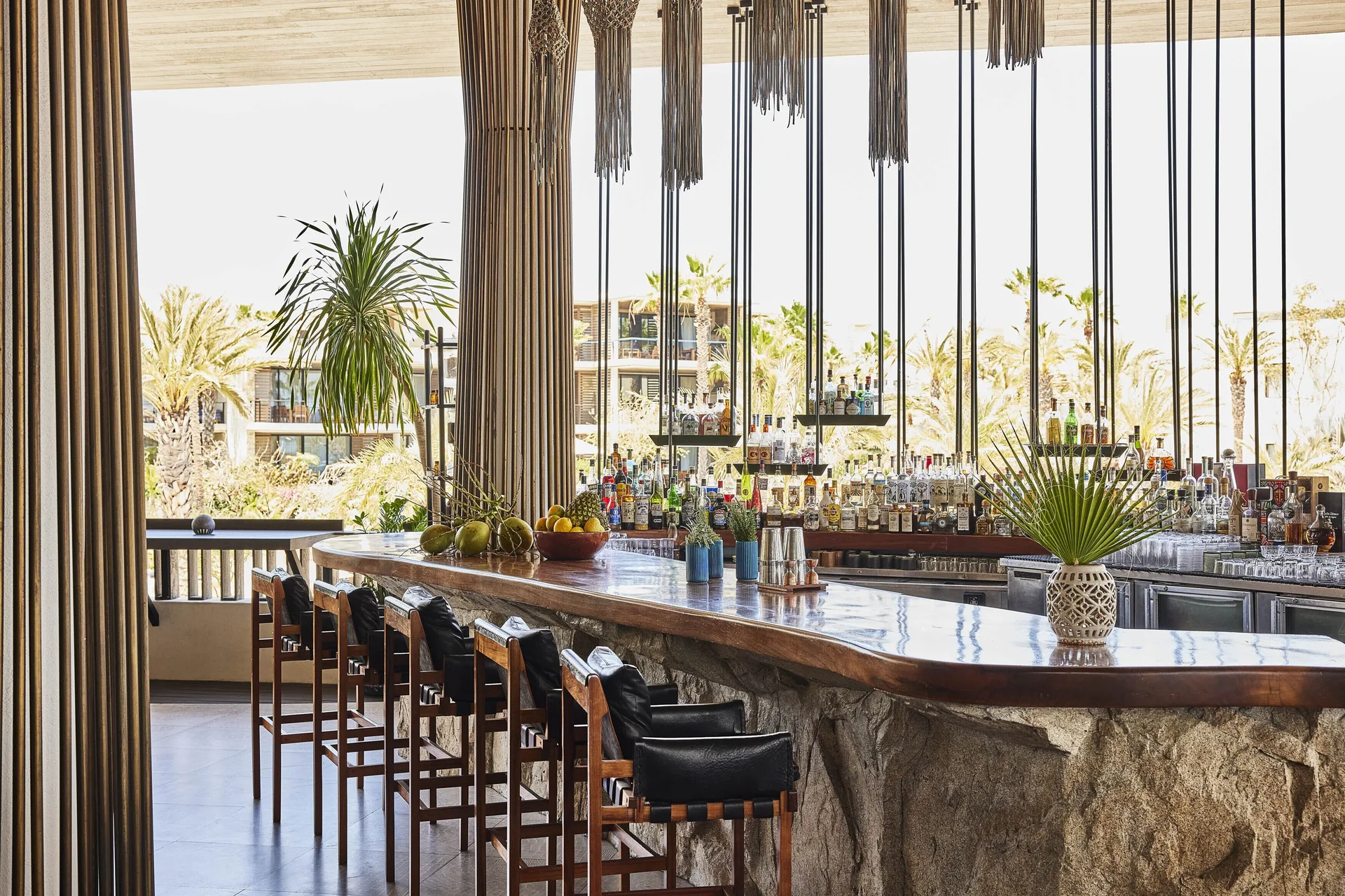 Stone bar with high stools and hanging decor at Chileno Bay Resort & Residences.