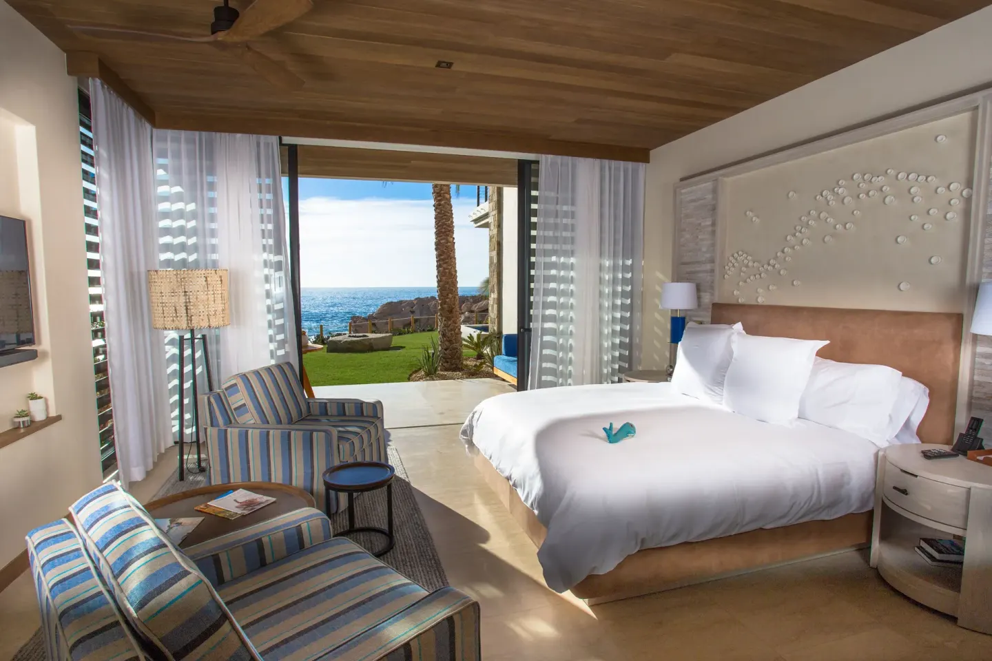 Oceanfront king room with striped seating and lawn view at Chileno Bay Resort & Residences.
