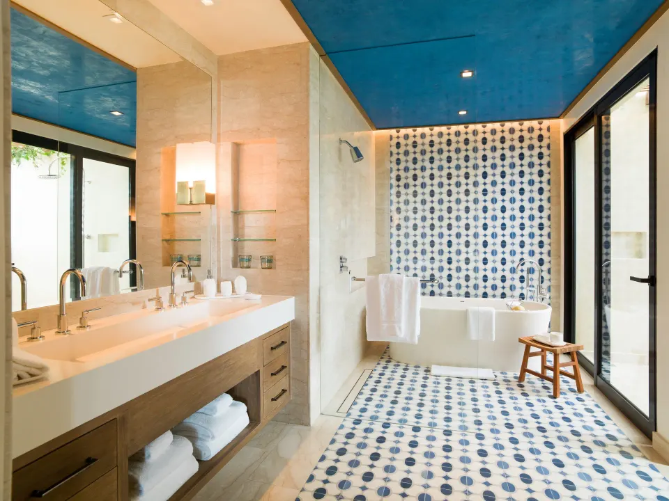Guest bathroom with double vanity, soaking tub, and blue tile at Chileno Bay Resort & Residences.