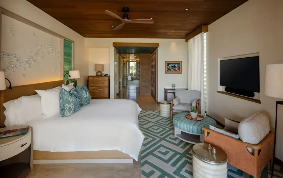 Resort-view guest room with king bed, sitting area, and TV at Chileno Bay Resort & Residences.