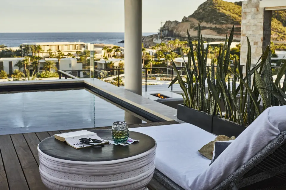 Poolside chaise on a Signature Villa terrace at Chileno Bay Resort & Residences with ocean beyond.