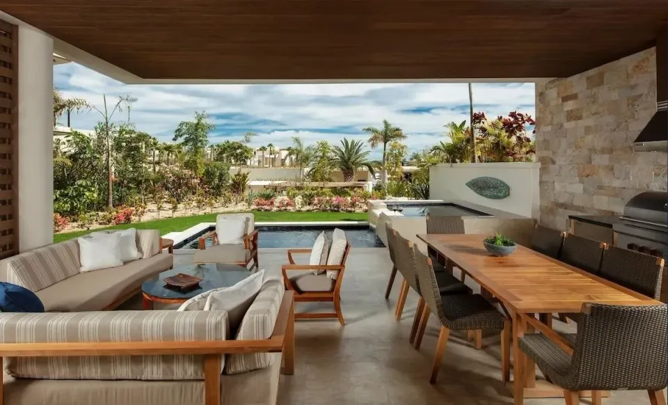 Covered villa terrace with outdoor dining, lounge seating, and pool at Chileno Bay Resort & Residences.