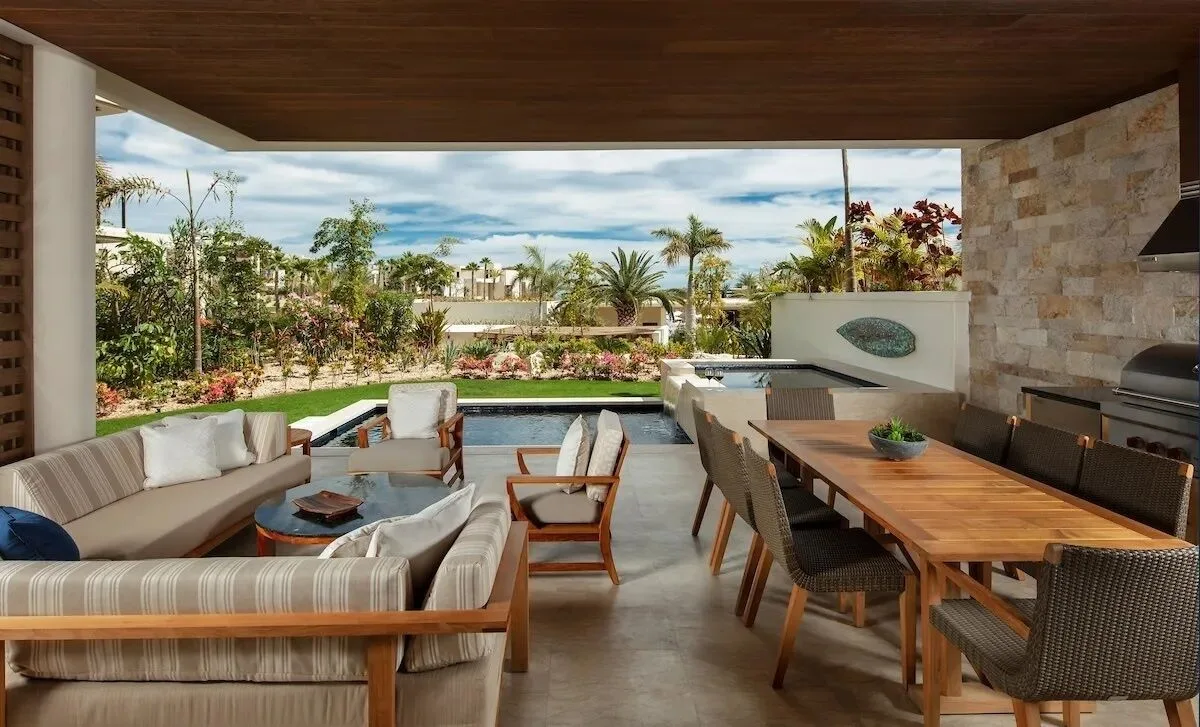 Covered villa terrace with outdoor dining, lounge seating, and pool at Chileno Bay Resort & Residences.
