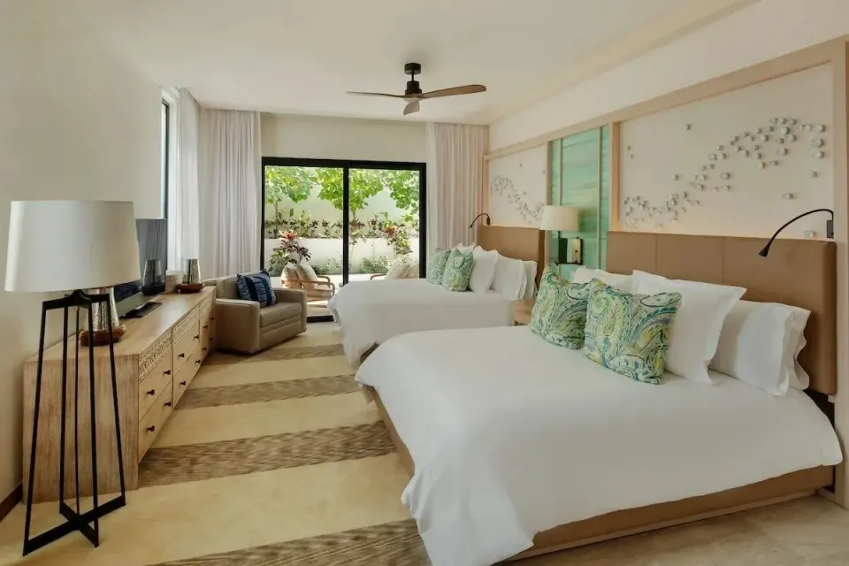 Bedroom with two beds and garden patio in a villa at Chileno Bay Resort & Residences.