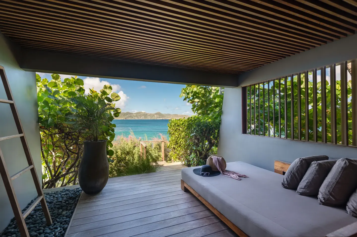 Covered terrace daybed looking out to the sea and gardens at Christopher Hotel.