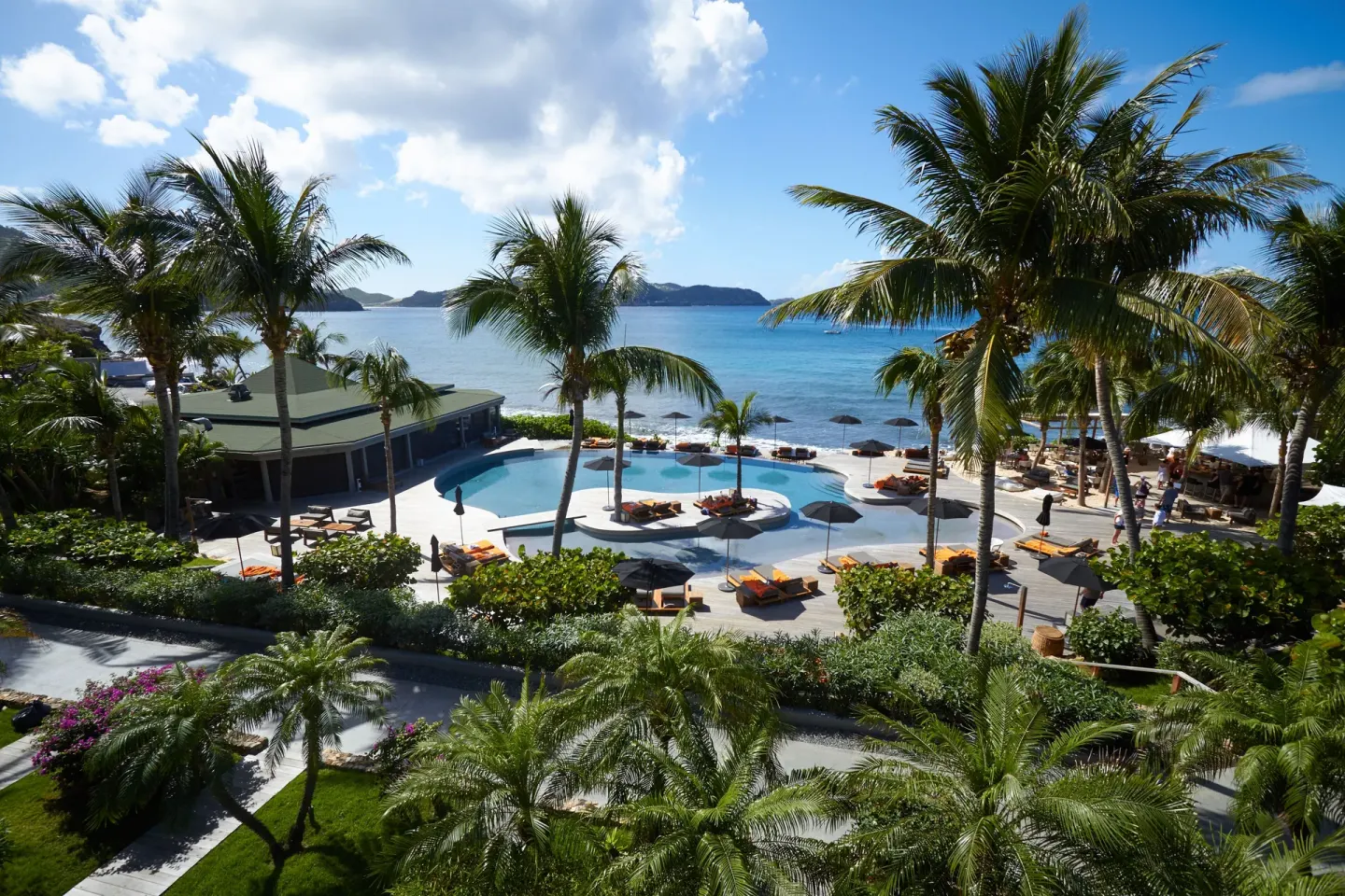 Elevated view of the pool, palms, and turquoise sea at Christopher Hotel.