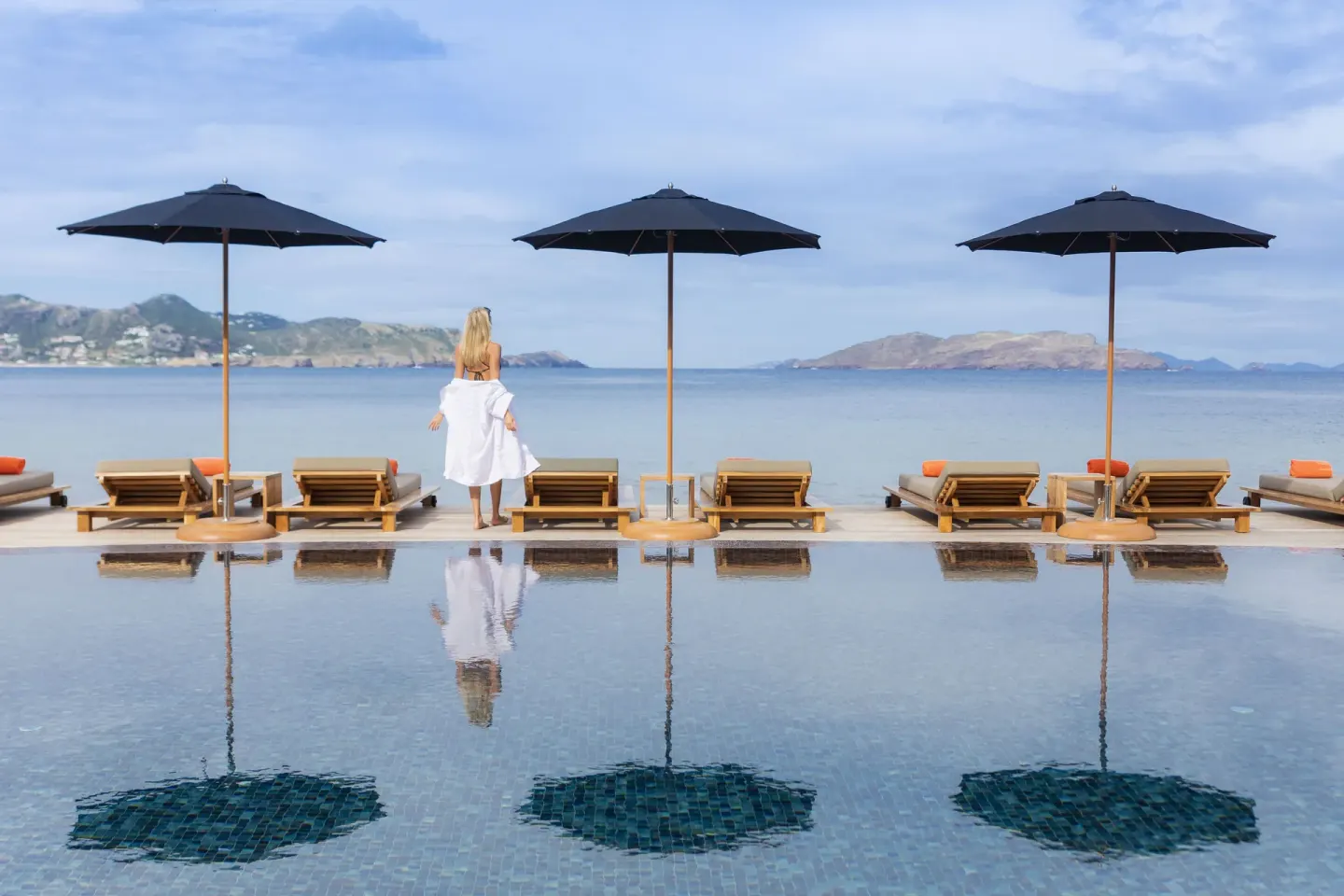 Guest by the infinity pool with umbrellas and island views at Christopher Hotel.