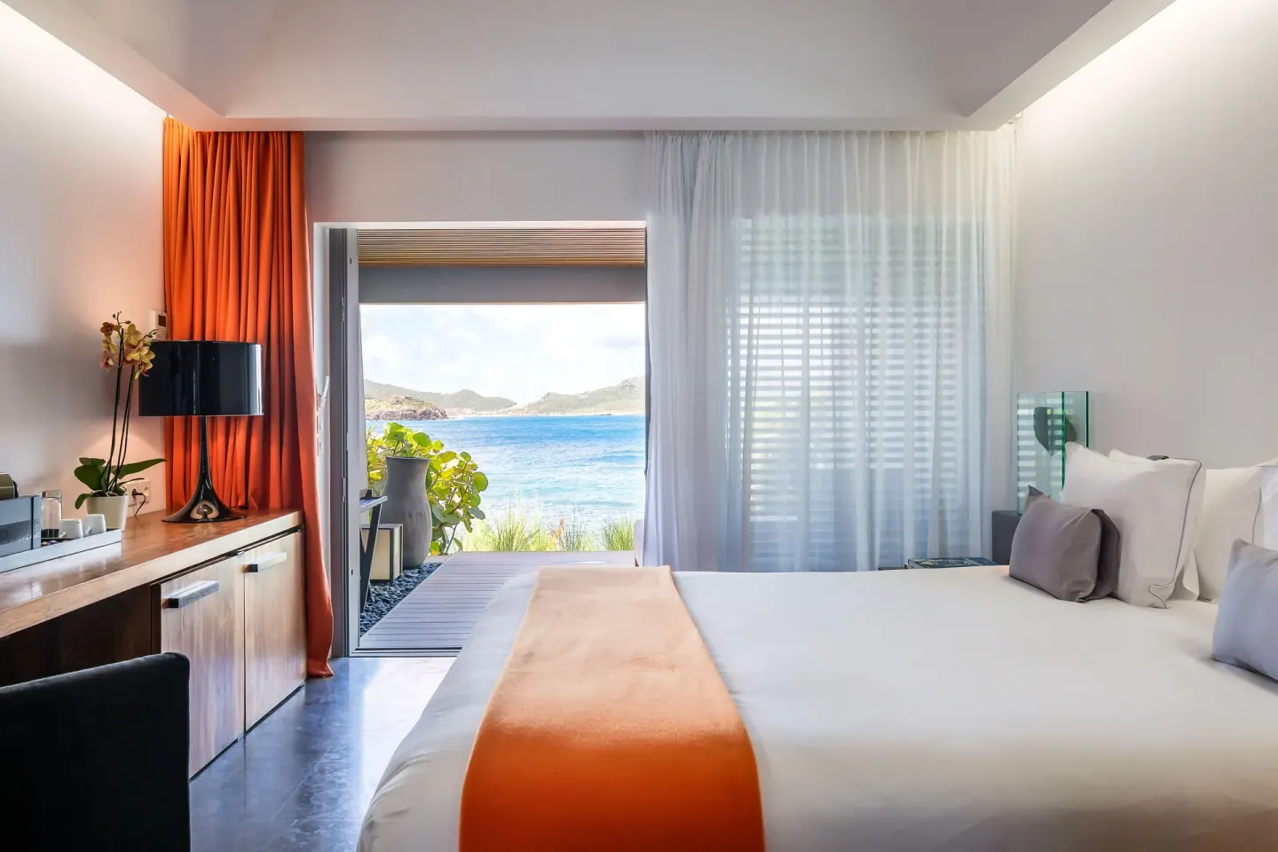 Ocean-view king bed guest room with orange accents at Christopher Hotel.