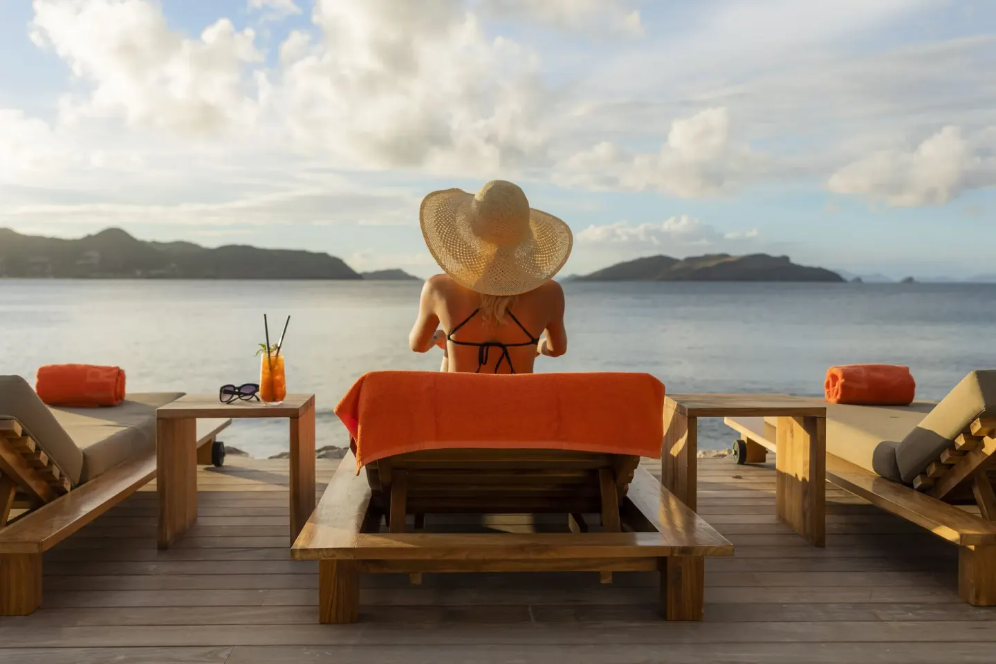 Guest relaxing on an oceanfront lounger with orange towels at Christopher Hotel.