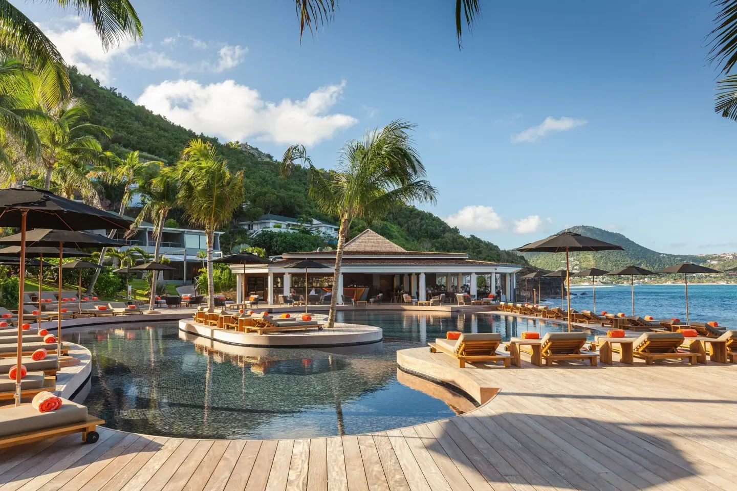 Pool deck with loungers, umbrellas, palms, and sea views at Christopher Hotel.