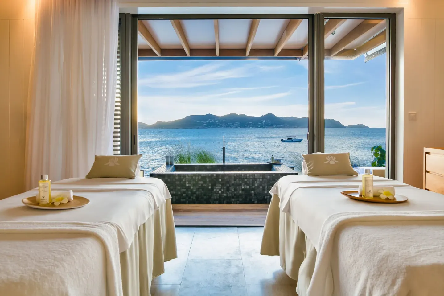 Two spa treatment beds face the sea through glass doors at Christopher Hotel.