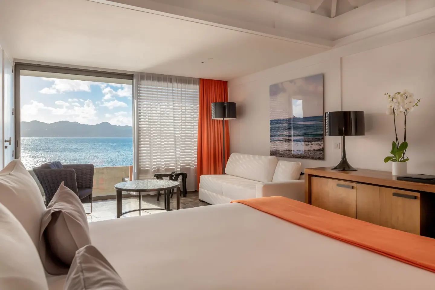 Guest room with king bed, sitting area, and sea-facing balcony at Christopher Hotel.