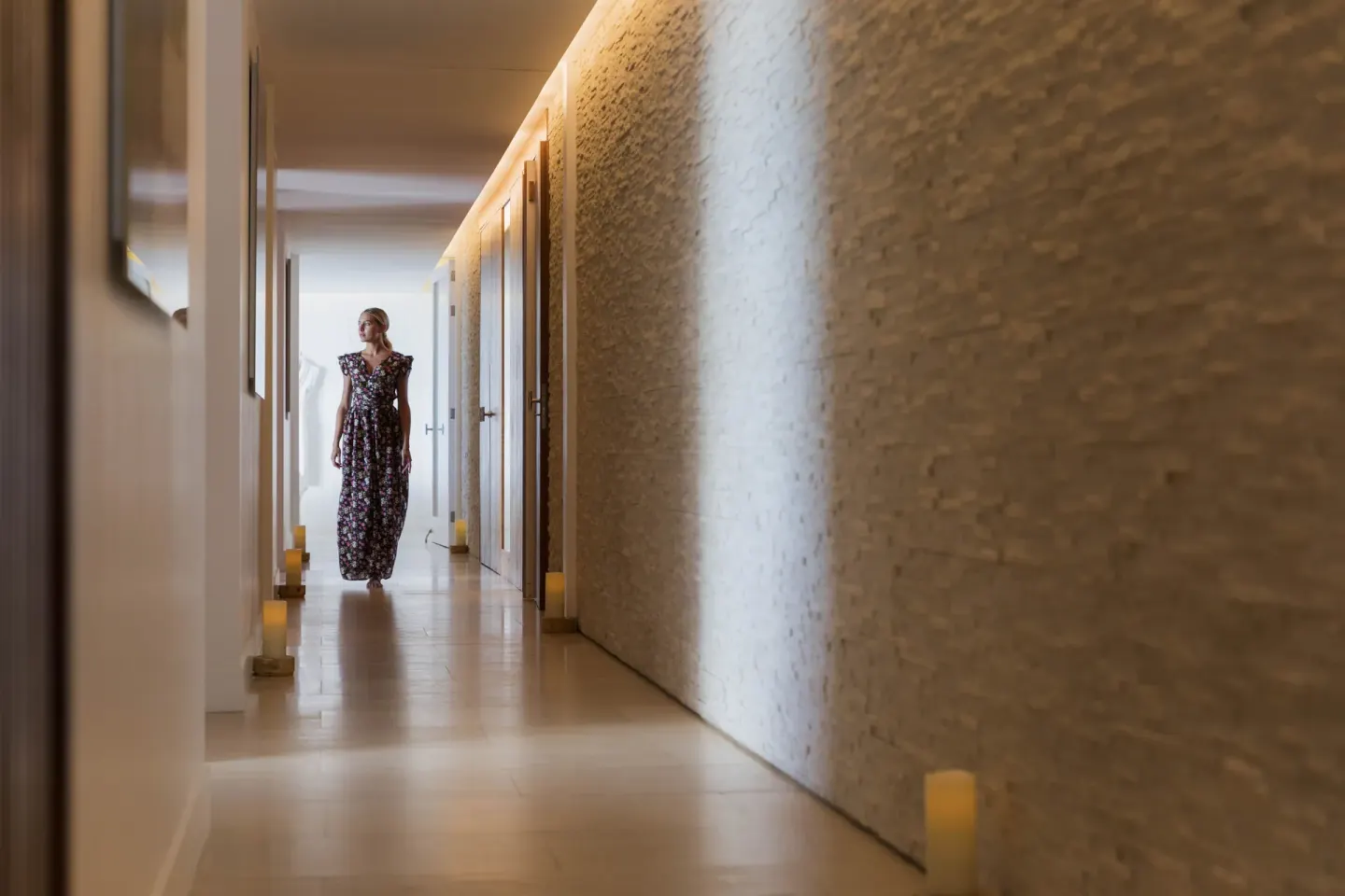 A softly lit spa corridor with candles and textured walls at Christopher Hotel.